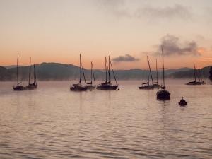沃尔特湖畔韦尔登Hotel Parks的日落时分在水中航行的一组帆船