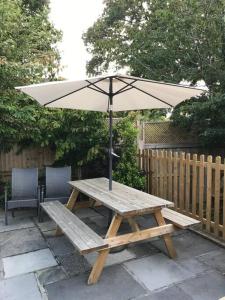 BroadstoneLovely detached garden chalet的庭院内一张带遮阳伞的木制野餐桌
