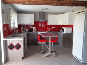 SazillyLe Gîte de Martine et Marc的厨房设有红色的墙壁和一张桌子及红色的椅子