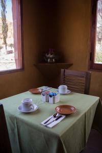 普尔马马尔卡samaywasi的一张桌子,上面有绿桌布,盘子和杯子