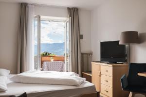 蒂鲁罗Hotel & Residence Rebhof的酒店客房设有一张床、一台电视和一扇窗户。