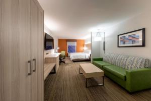 彼得斯堡Holiday Inn Express Hotel & Suites Petersburg/Dinwiddie, an IHG Hotel的酒店客房带绿色的沙发和一张床