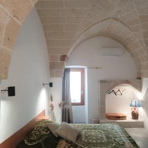 莱韦拉诺Antica Dimora Salentina的一间带一张床铺的卧室,位于带拱门的房间