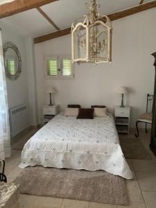 旺斯le mas des roses 1884的卧室配有白色的床和吊灯。