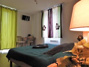 Villeneuve-dʼEntraunesLe Relais des Cavaliers的一间卧室配有床和两个带绿色窗帘的窗户。