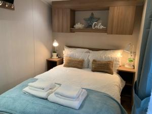 浦耳Cosy, coastal themed Holiday Home, Rockley Park, Poole, Dorset的一间卧室配有带毛巾的床