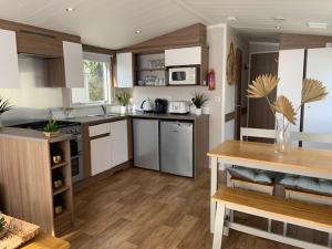 浦耳Cosy, coastal themed Holiday Home, Rockley Park, Poole, Dorset的一间铺有木地板的大厨房,配有白色的橱柜