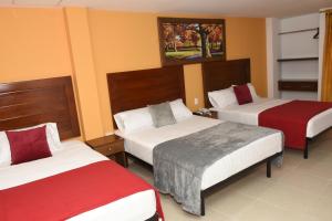 SoledadHotel Kai Soledad Atlántico的酒店客房带两张红色和白色的床单