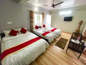 博卡拉丰收圆月乡村民宿的一间卧室配有两张带红色枕头的床