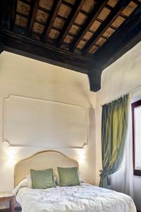 锡耶纳马尼菲科宫殿住宿加早餐旅馆的卧室配有带绿色枕头的白色床