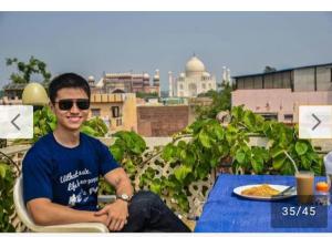 阿格拉Hotel Sai Palace Walking Distance From Taj Mahal--View of Taj Mahal的坐在餐桌上吃一盘食物的人