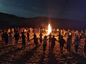 敦煌敦煌鸣沙山野奢国际沙漠度假酒店的一群人在海滩上的火堆旁跳舞