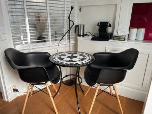 萨森海姆Prins Heerlijk的厨房里配有两张黑椅子和一张桌子