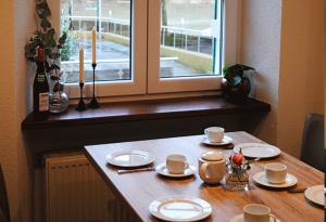 赖尔Gästehaus Weingut Schier im historischen Zehnthof的一张桌子,上面有盘子和杯子,还有一个窗口