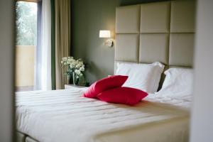 瓦瑞诺博吉博尔基别墅酒店的白色床上的2个红色枕头,设有窗户