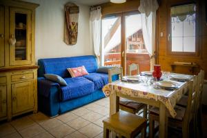 莱德萨阿尔卑斯T2 Meublé Tourisme 3 etoiles, pied des pistes-parking privé avec balcon et superbe vue的客厅配有桌子和蓝色沙发