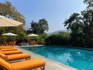 VichondremThe Postcard Hideaway, Netravali Wildlife Sanctuary, Goa的一个带橙色椅子和遮阳伞的游泳池