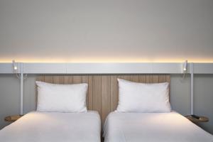 安锡Ibis Annecy - Cran-Gevrier的两张带白色枕头的床,彼此相邻
