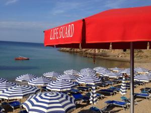 阿祖罗港朱利亚别墅酒店的海滩上的一组椅子和遮阳伞