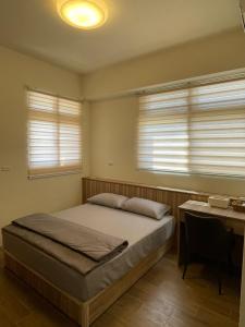 马公欣雅民宿的一间卧室配有一张床、一张书桌和两个窗户。
