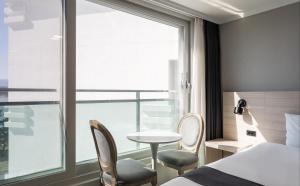 江陵市Gyeongpo Soo Hotel的酒店客房带一张床、一张桌子和椅子