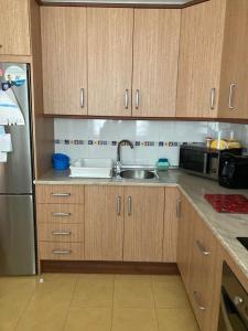 阿尔么丽亚Apartamento El Toyo的厨房配有木制橱柜、水槽和冰箱。