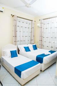 达累斯萨拉姆机场中转山林小屋的蓝色和白色的客房内的两张床