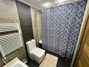 朱拜勒Panoramic Sea View 2 Bedroom Apartment的浴室设有卫生间和蓝白色的浴帘。