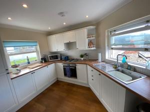 马伯斯Extended Fishermans cottage with stunning sea views的厨房配有白色橱柜和水槽