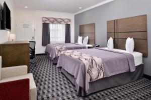 亨博尔Americas Inn & Suites IAH North的酒店客房配有两张床和一张书桌