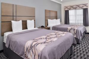亨博尔Americas Inn & Suites IAH North的酒店客房设有两张床和窗户。
