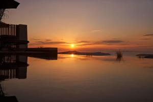 皮尔戈斯Apikia Santorini的日落在水体上,日落在太阳下