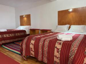 普诺Hotel Wiñay Pacha Inn的两张位于酒店客房的床,配有毛巾