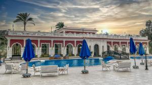 亚历山大Helnan Palace Hotel - Adults Only的一个带游泳池、椅子和遮阳伞的度假村
