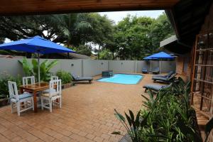 圣卢西亚Rhino Coast Guesthouse的一个带游泳池、椅子和遮阳伞的庭院