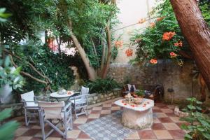 雷夫卡达镇Beautiful Traditional House in Lefkada的庭院设有2张桌子和椅子,树木繁茂。