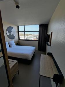 拉罗谢尔B&B HOTEL La Rochelle Centre Les Minimes的配有一张床、一张书桌和一扇窗户的酒店客房