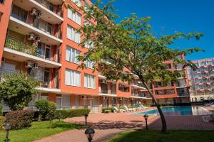 阳光海滩Sunset Beach - Menada Apartments的公寓大楼设有游泳池和树