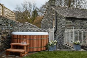 安布尔塞德Little Nut Cottage的庭院里的木制热水浴缸和木桌