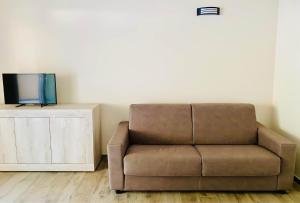 皮诺港Nuova Residenza dei 7 Pini a pochi passi dal mare的客厅设有一张棕色沙发,配有电视