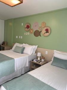 巴雷里尼亚斯Gran Lençóis Flat Residence Mandacaru 311 - 611的两张位于酒店客房的床,墙上挂着帽子