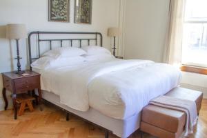 波茨坦Pert House的一间卧室配有一张带白色床单和桌子的大床