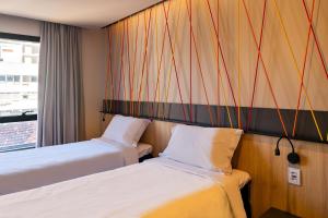 阿雷格里港ibis Styles Porto Alegre Moinhos de Vento的酒店客房设有两张床和窗户。