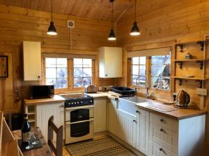 滕比The Chalet @ Giltar Grove Country House的厨房配有白色橱柜和炉灶烤箱。