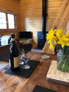 滕比The Chalet @ Giltar Grove Country House的木桌上放一瓶葡萄酒和玻璃杯