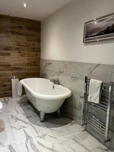 格拉斯哥WEST END -Stunning, 2 bedroom, main door flat with private parking的浴室铺有大理石瓷砖,配有白色浴缸。