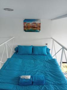 BaronBaron Lighthouse Cottage & Eatery的卧室内的一张蓝色的床,墙上挂着一幅画