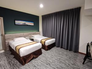 关丹美利通酒店的酒店客房设有两张床和绿色的墙壁。