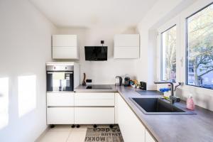 莱茵河畔路德维希港Komfort Deluxe的厨房配有白色橱柜、水槽和窗户。