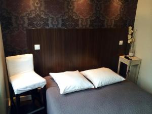 瓦朗斯莱斯尼古奇安特斯酒店的一张带两个枕头的床和一把椅子